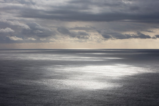 Storm clouds clearing over expansive ocean, dappled sunlight on water, northern Oregon coast,Clearing storm clouds and dappled sunlight on vast ocean at dusk