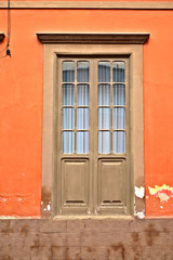 A decorative tall brown classic window with many small glass panes, old architecture detail.
