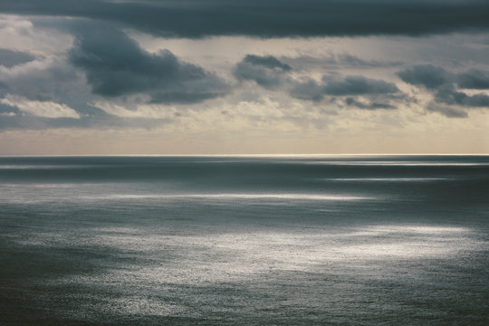 Storm clouds clearing over expansive ocean, dappled sunlight on water, northern Oregon coast,Clearing storm clouds and dappled sunlight on vast ocean at dusk