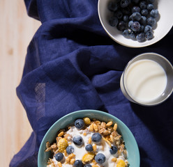 Bowl with oatmeal, raspberries and a glass of milk on a white wooden background.