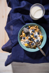 Bowl with oatmeal, blueberries and a glass of milk on a white wooden background