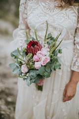 Bride in a white, modern lightweight dress posing. Wedding floral bouquet in her hands. Vintage hipster bride, warm colors.