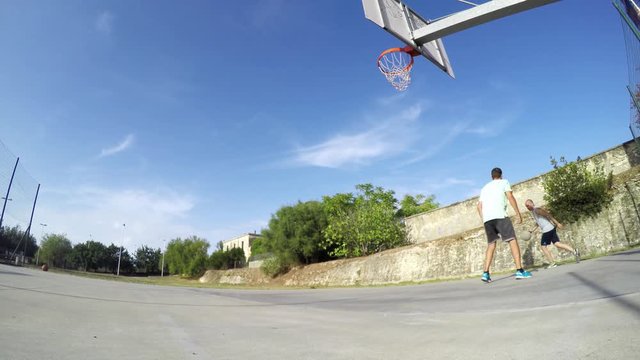 Two guys playing basketball on a clear summer day