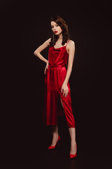 Fototapeta na wymiar Full length of beautiful woman in red dress looking at camera isolated on black