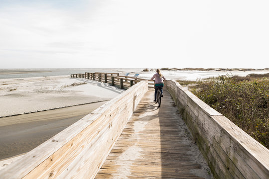 teen girl on her bike crossing bridge to the beach, St. Simon's Island, Georgia