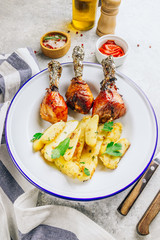 Grilled chicken drumstick bbq with potato slices on a stone gray background.