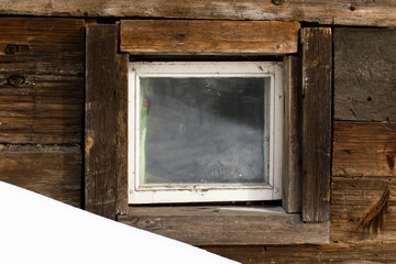 small wooden window on a background of an old wooden wall.