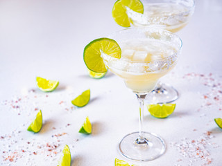 Two Margaritas on the marble table with lime and salt. Alcohol cocktail at the bar. Mexican national drink. Fresh summer party tequila drinks.  