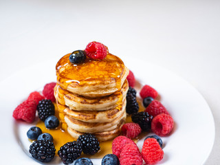 Pancakes for breakfast with raspberries and maple syrup. Fluffy and delicious buttermilk pancakes. Beautiful and healthy fresh food. Home made brunch with berries.