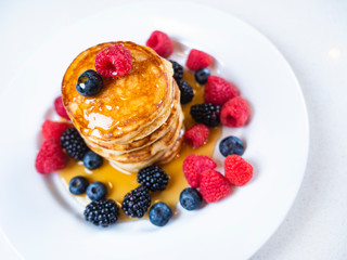 Pancakes for breakfast with raspberries and maple syrup. Fluffy and delicious buttermilk pancakes. Beautiful and healthy fresh food. Home made brunch with berries.