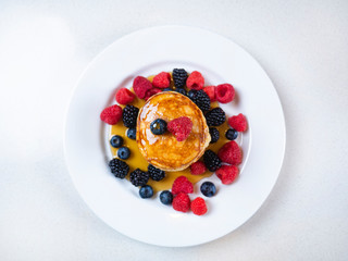 Pancakes for breakfast with raspberries and maple syrup. Fluffy and delicious buttermilk pancakes. Beautiful and healthy fresh food. Home made brunch with berries.