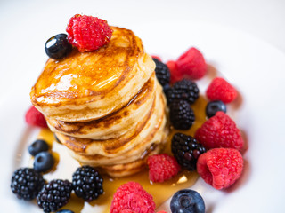 Pancakes for breakfast with raspberries and maple syrup. Fluffy and delicious buttermilk pancakes. Beautiful and healthy fresh food. Home made brunch with berries.