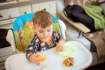 a small child eats on their own. the baby eats himself. the little boy is eating.