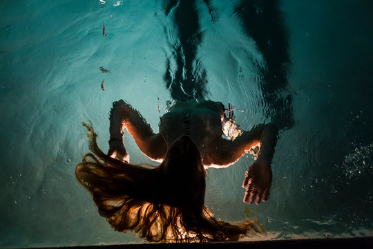 Two children swimming in pool at night