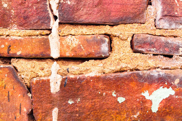 The texture of an old brick wall with patches of cracked and broken cement. Brown broken brickwork...