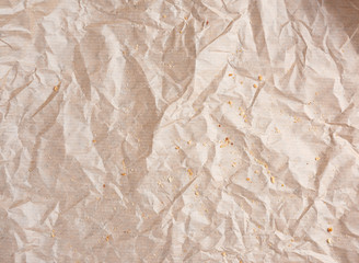 crumpled brown parchment paper with bread crumbs