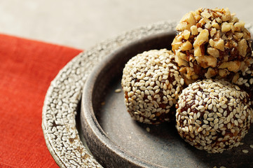 Oatmeal energy balls covered with sesame and walnut crumbs close-up, lying on a ceramic plate. Copy space, healthy food, trend..