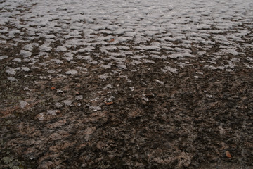 Scale on the rough surface of the pinkish old granite block