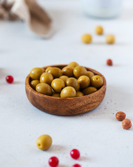 Healthy snack. Food photo of green ripe olives in a wooden plate on a light background.