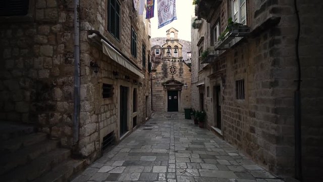 Church in narrow street. Dubrovnik Old Town, Croatia. Famous fortress. Historic centre of Croatia, major tourist attraction in Europe in summer. Glide shot. 