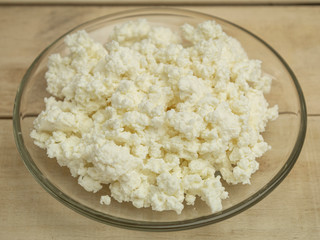 Cow milk curd in glass plate on wooden background
