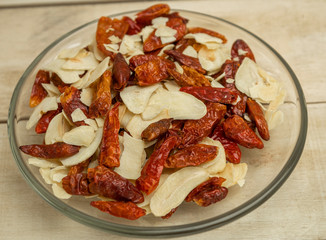 Dried garlic spices and hot pepper in a glass plate on wooden background