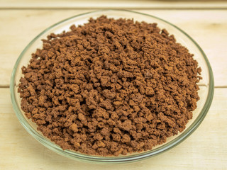 Granulated coffee in a glass plate on a wooden background