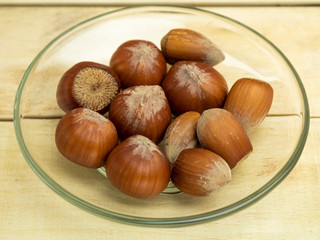 Hazelnuts in a glass plate on a wooden background