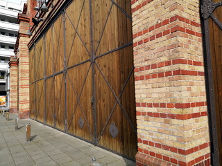 Sorgfältig restauriertes Mauerwerk aus Backstein mit braunem Holztor am Bockenheimer Depot im...