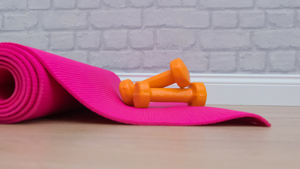 Two dumbbells for sport on the pink yoga mat.