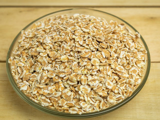 Oat groats in a glass plate on a wooden background