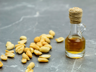 Oil in a bottle and nuts on a marble background