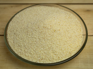 Semolina in a glass plate on a wooden background