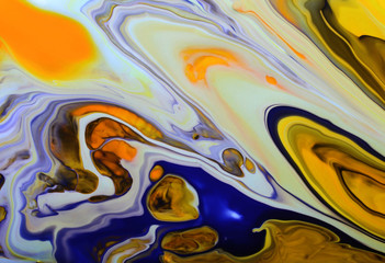 Colorful marble background.Mixed nail polishes-yellow,orange,blue,and other.Beautiful stains of liquid nail polish,fluid art technique.Pour painting artwork.