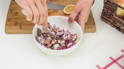 Chopped fresh red onion marinated with lemon juice and soy sauce close up in a bowl on a kitchen table