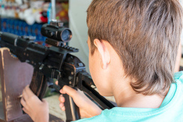 Caucasian teenage boy aiming with pneumatic rifle in shooting gallery, range