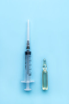 Medical ampoule with the drug and a disposable syringe on a blue background. Medicine infectious concept.