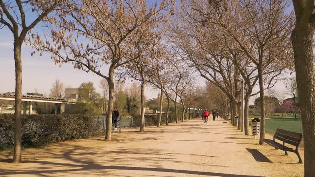 People enjoy outdoor sports and leisure activities early spring in an urban park in Madrid, Spain. A huge green park and recreational area with a train and sculptures for leisure and sport activities.