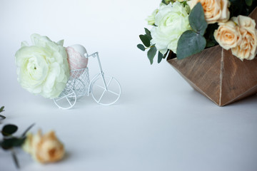 Rustic Easter composition with egg decorated ribbon lace, white little bicycle with fabulous ranunculus and flowers composition. Side view.