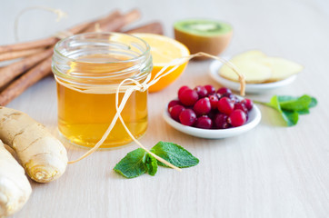 honey, lemon, cranberries, kiwi, cinnamon, ginger root on light wooden background with copy space....