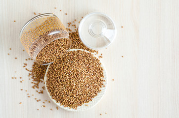 top view of buckwheat porridge in glass jar for storing cereals, grains on light wooden background with copy space