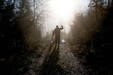 Man searching treasure in the wood with metal detector at sunrise in autumn. Success concept