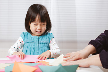 toddler girl learn making  Origami at home against white background