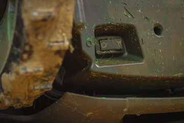 Dirty switch of robotic lawnmower, motorized lawnmower being serviced on a table after a year of use in the mud and grass. On-off switch on robotic lawnmower.
