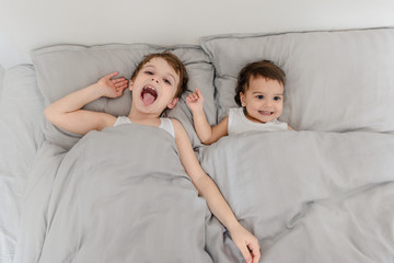 Top view of brother an sister child in white t-shirts waking up