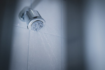 Dirty shower head wirth spraying water out of it. Dirty shower in a bathroom, lime or limestone...