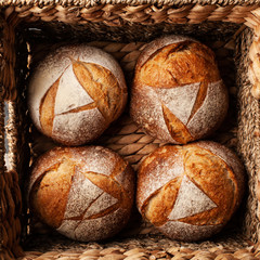 4 loaves of wheat bread in a wicker basket. top view. Wholemeal rustic bread concept