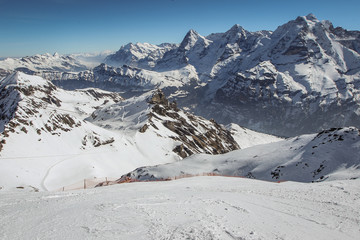 Beautiful alpine panorama on a sunny day from the top of Schilthorn, Switzerland, peak above Murren. Gorgeous landscape in switzerland with steep skiing slope