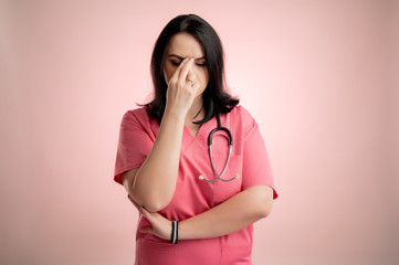 Beautiful woman doctor with stethoscope, wearing pink scrubs wondering