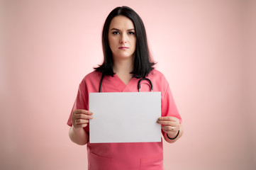 Fototapeta na wymiar Beautiful woman doctor with stethoscope, wearing pink scrubs holding a white paper